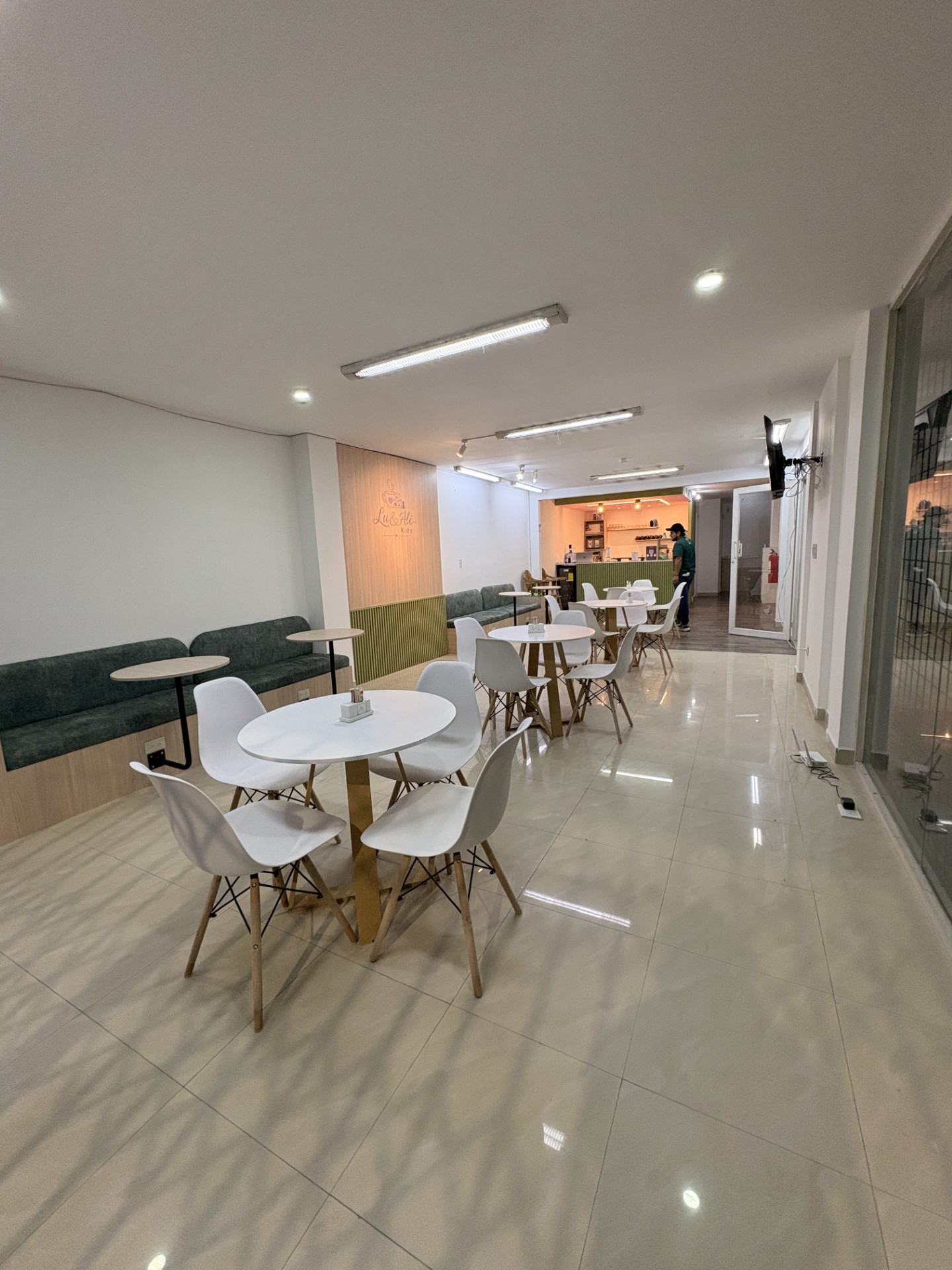 Área de mesas de la cafetería con juegos para niños de Lu & Alé Kids en Quito Norte